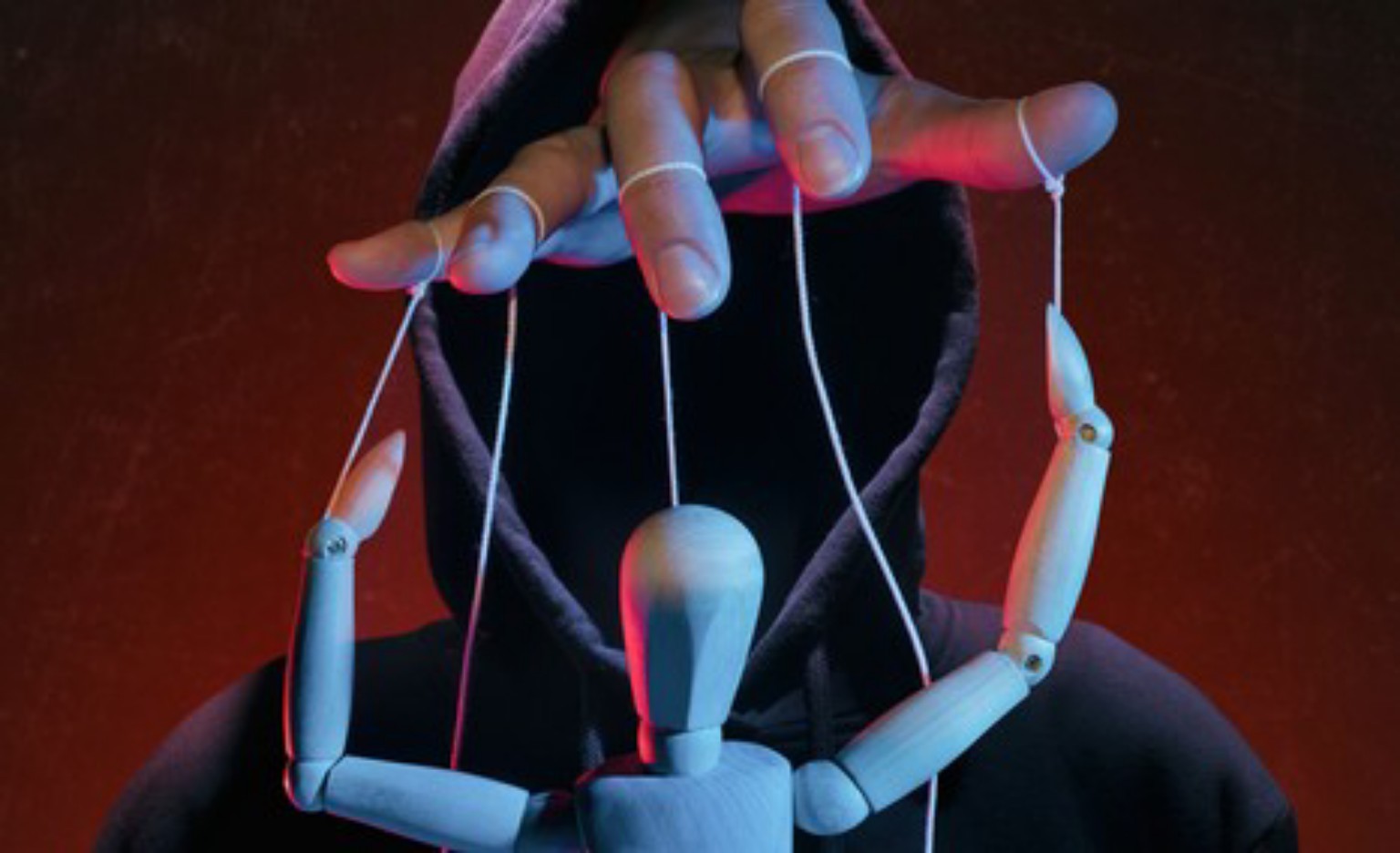 Une figure encapuchonnée tient les fils d’une marionnette