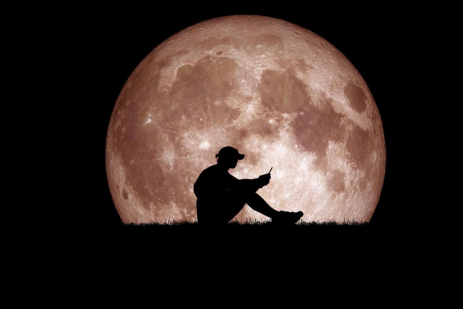 Une silhouette assise devant une lune lumineuse