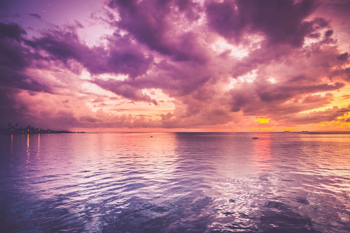 Des nuages roses et violets se reflètent dans l’océan